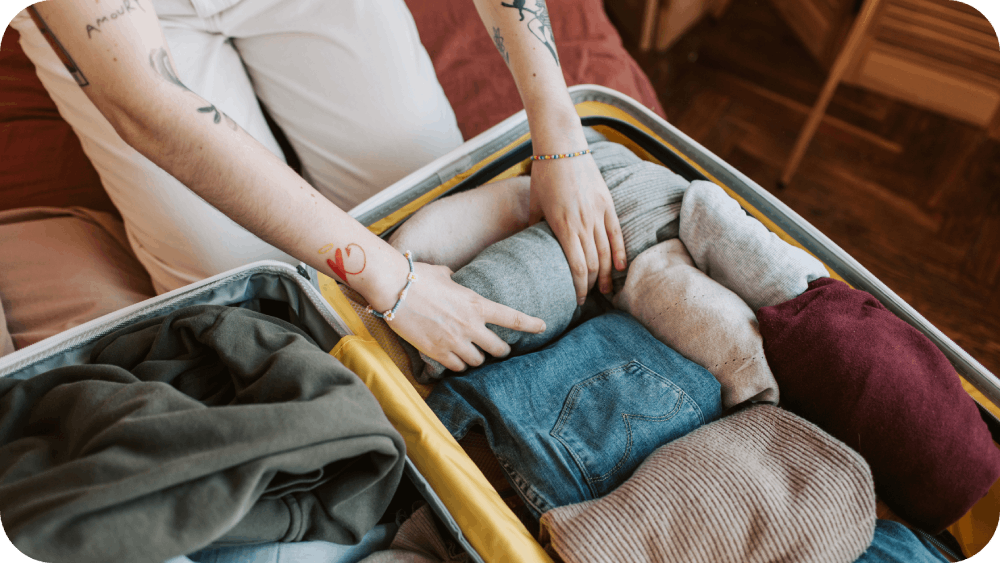 Person folding clothes and packing his luggage